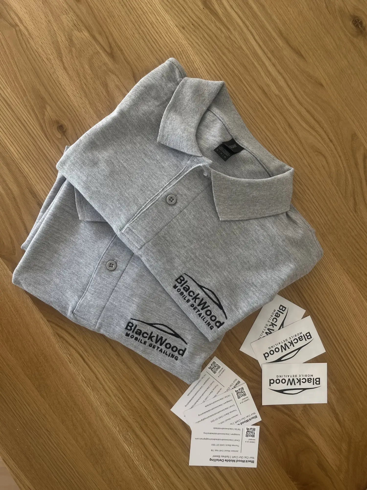 BlackWood Mobile Detailing embroidered polo shirts and business cards on a timber table